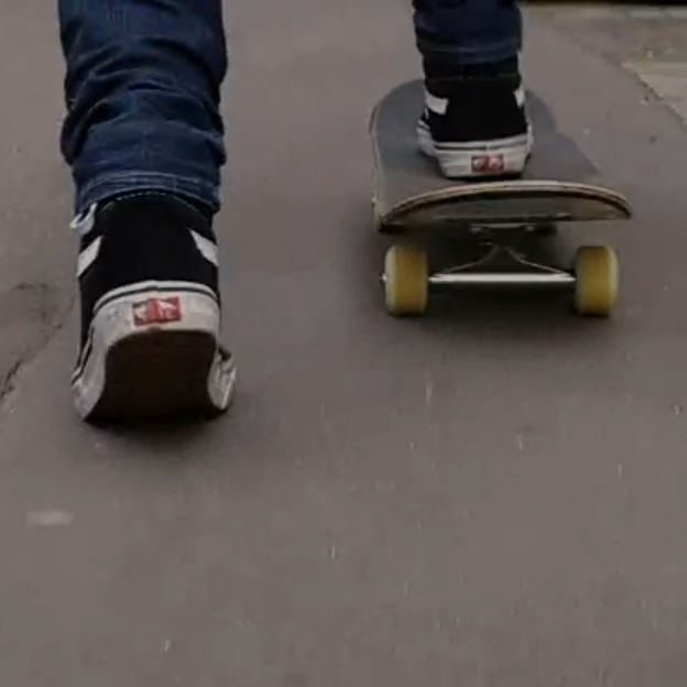 Ein Fuß auf einem Skateboard. Der andere Fuß holt Schwung am Boden.