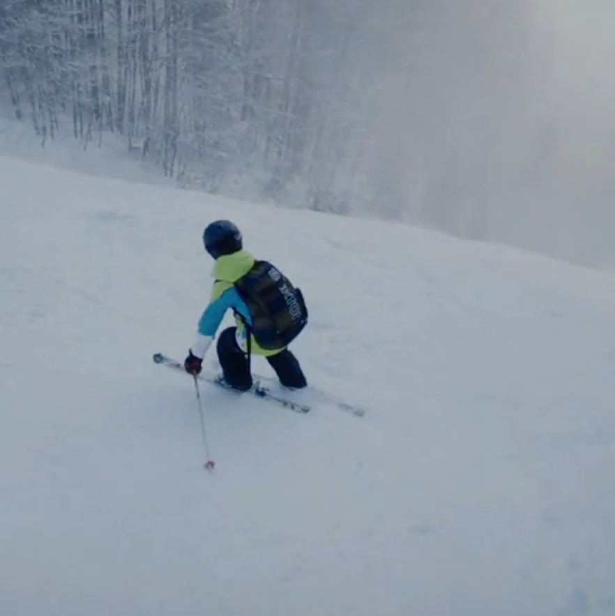 Ein Junge fährt in den Bergen Skier. Er fährt einen steilen und nebeligen Hang.